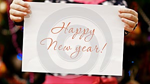 Two child`s hands hold a piece of paper with a congratulation happy new year