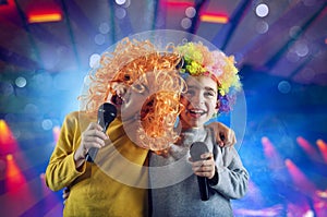 Two child sing a song with microphone and funny wig photo