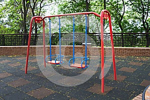 Two child swings in empty playground due coronavirus. Safety for children. Injury due to a fall. Baby swings metal.