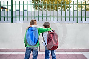 Two children with backpacks on their backs hugging. Back to school concept
