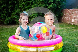 Two children with beach ball at swimming pool. Joyful kid playing in inflatable pool backyard. Little kids at swimming pool on