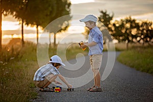 Two children, boy brothers, having fun outdoors with toy cars