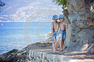 Two children, boy brothers, walking on a path around mediterranian sea on French riviera