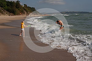 Two children a boy and a girl, a brother and a sister are playing on the seashore in the water.