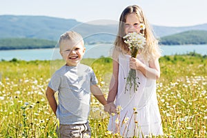 Two children boy and girl at camomile field