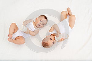 Two children a boy and a girl-twins of 8 months drink milk from a bottle on the bed in the nursery, feeding the baby, baby food