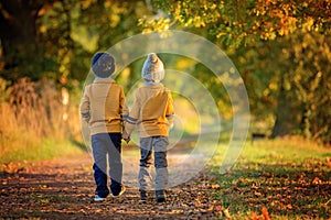 Two children, boys, walking on the edge of a lake on a sunny autumn afternoon