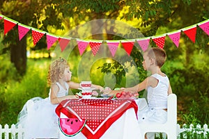 Two children brother and sister eat and drink on beautiful decorated picnic. Hungry kids boy and girl eating outdoors. What to do