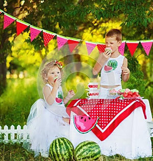 Two children brother and sister eat sweet cupcakes on beautiful decorated picnic. Hungry kids boy and girl eating outdoors. What