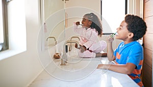 Two Children Brushing Their Teeth In Bathroom At Home