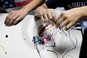 two children build a prototype circuit with a red laser controlled by a microcontroller. STEAM and coding activity