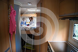 Two children on a campervan bed during a road trip stop