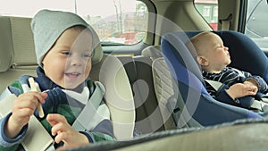 two children car seat sit travel inside car elder boy smiling baby brother cry