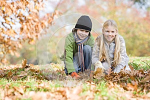 Two children collecting leaves