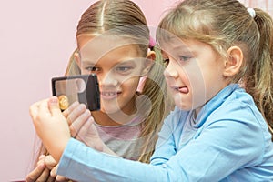 Two children considered coin through a magnifying glass photo