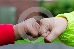 Two children of different races greeting each other with fist bump. Photo shows friendship, support, equality and diversity. One