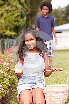 Two Children On Easter Egg Hunt In Garden