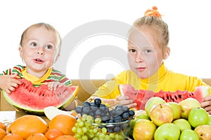 Two children eat fruit at a table