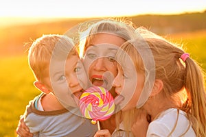 Two children eat lollipop with mother