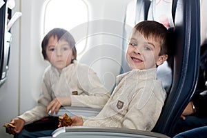 Two children, eating sandwiches on board in aricraft, traveling