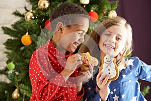 Two Children Eating Treats In Front Of Tree