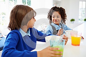 Two Children Having Breakfast Before School In Kitchen