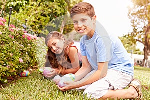 Two Children Having Easter Egg Hunt In Garden