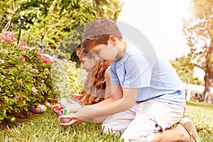 Two Children Having Easter Egg Hunt In Garden