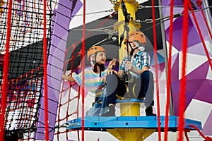 Two children in helmets climb on tightropes