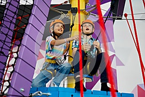 Two children in helmets climb on tightropes