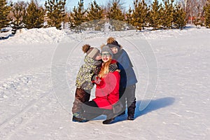 two children hug smiling mother in the snow in the winter. Happy family. people in outer clothing