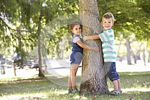 Two Children Hugging Tree In Park