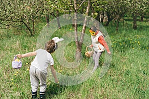 Two children hunt for Easter eggs in a spring garden. Easter tradition