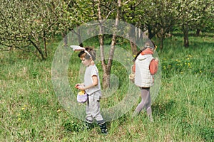 Two children hunt for Easter eggs in a spring garden. Easter tradition