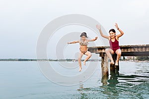 Two children jumping from the bridge in the water
