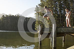 Two Children Jumping From Jetty Into Lake