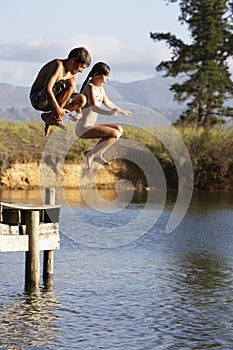 Two Children Jumping From Jetty Into Lake