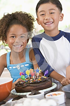 Two children in kitchen with birthday cake