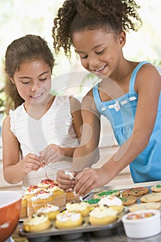 Two children in kitchen decorating cookies