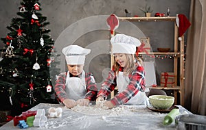 Two children kneading dough together, brother and sister making Christmas cookies, baking in the kitchen. Copy space