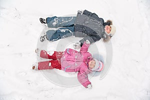 Two children lie on snow