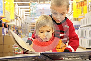 Two children look book in store