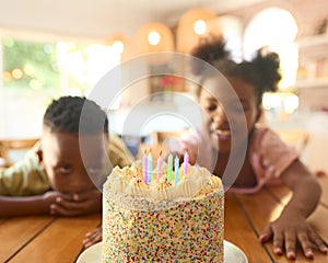 Two Children Looking Hungrily At Tasty Birthday Cake On Table For Party photo