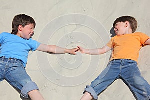 Two children lying nearby on sand