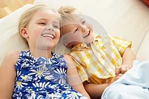 Two Children Lying Upside Down On Sofa At Home