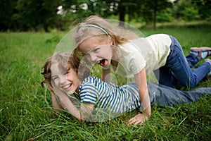 Two children are naughty on a green grass.