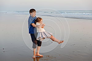 Two children on ocean beach. Teenager boy and little preschool sister having fun by sunset. Sea vacation for family