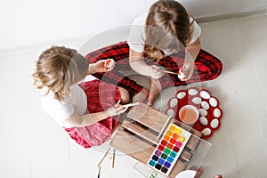 Two children paint eggs with watercolors, Easter