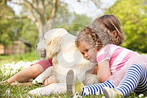 Two Children Petting Family Dog In Summer Field