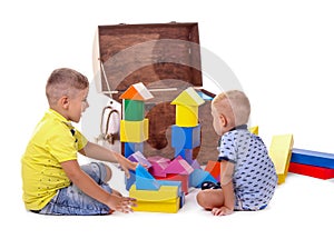 Two children play with eco-cubes. A big wooden brown box and many different multicolored toys for children, isolated on